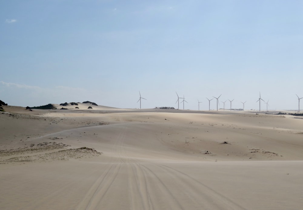 wind turbines on brown sand under blue sky during daytime