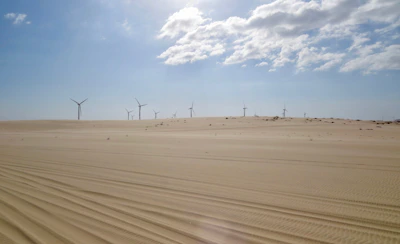 Technicians from Nouralbahr inspecting wind turbines against a clear desert sky.