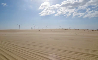 Technicians from Nouralbahr inspecting wind turbines against a clear desert sky.