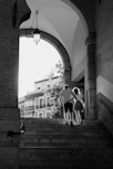grayscale photo of man and woman walking on sidewalk