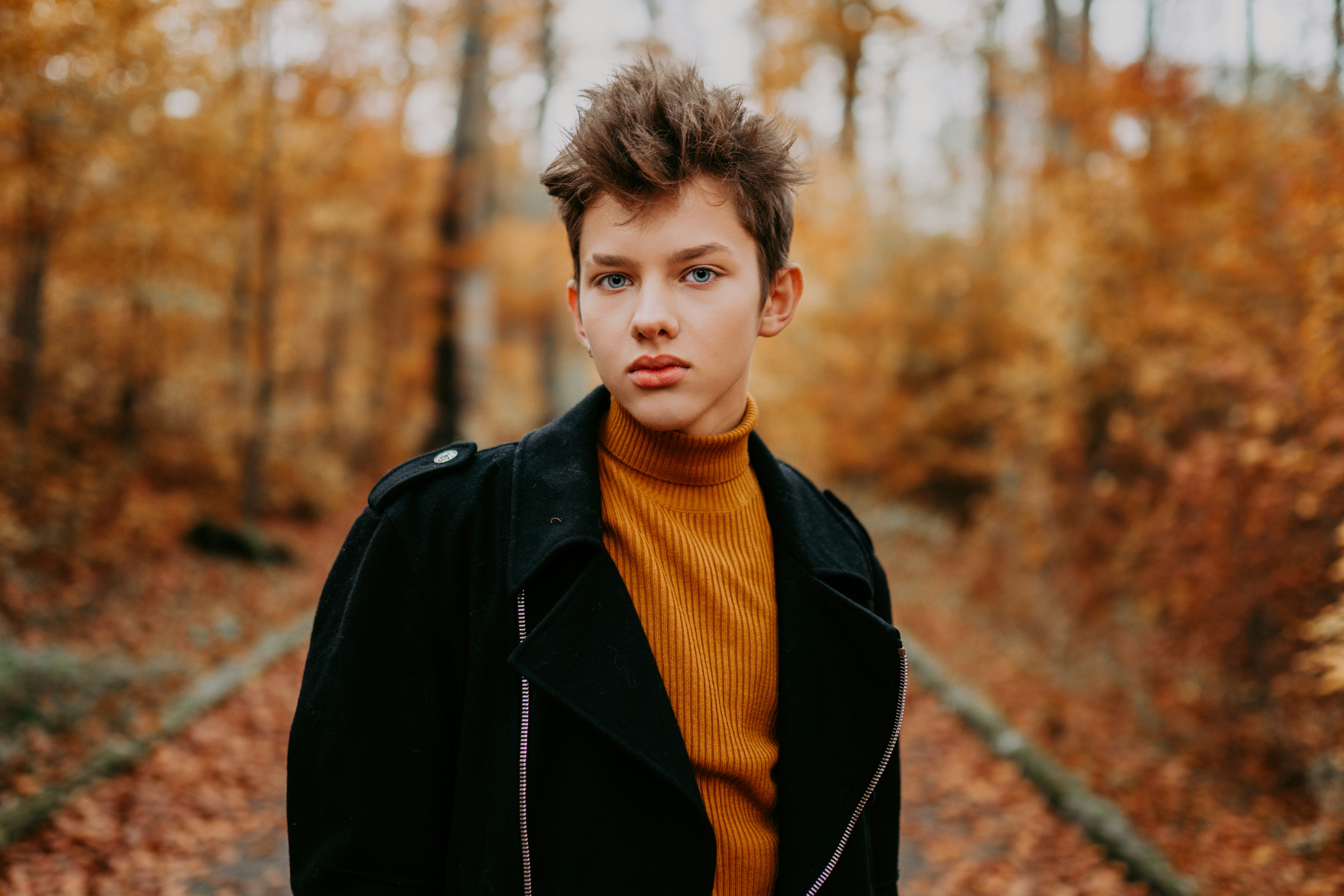 man-in-black-leather-jacket-standing-near-brown-trees-during-daytime