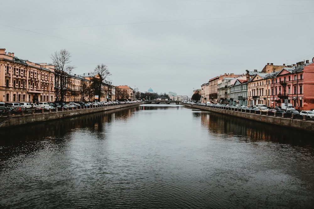 brown and white concrete building beside river under white sky during daytime