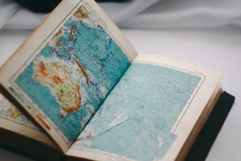 An open book displaying a detailed map, focusing on a region with both water and landmasses. The map includes various colors to differentiate between countries or geographic areas.