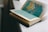 An open book with pages containing detailed maps, placed on a light-colored surface. The map on the visible page appears to show geographical regions in shades of blue, green, and brown.