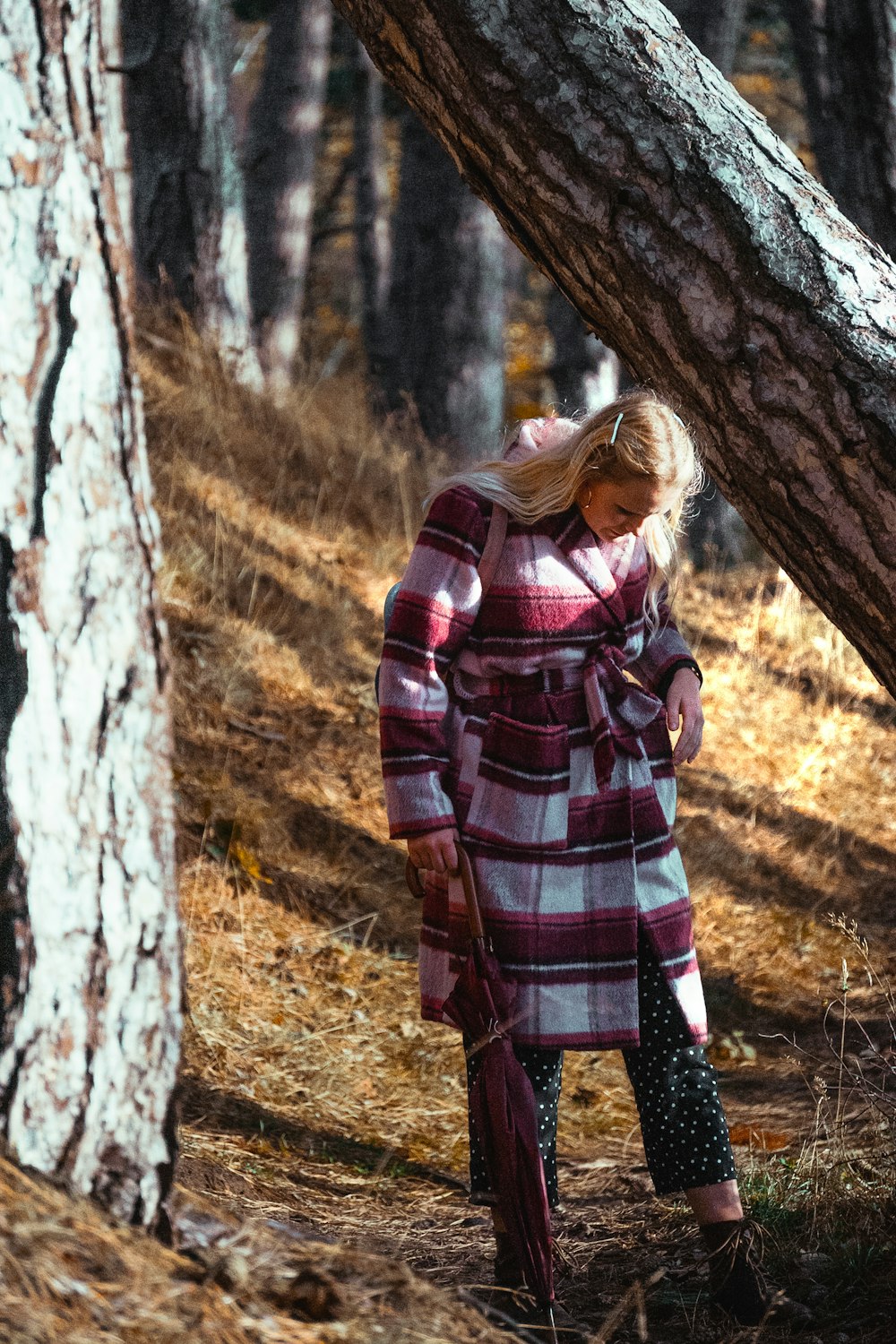 woman in red and black plaid coat standing beside tree