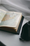 Close-up of a hand holding a historical novel with an antique map in the background.