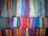 Multiple bundles of colorful yarn hanging in rows, showcasing a wide variety of shades and textures. Each bundle consists of tightly arranged threads, creating a vibrant display.