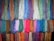 Multiple bundles of colorful yarn hanging in rows, showcasing a wide variety of shades and textures. Each bundle consists of tightly arranged threads, creating a vibrant display.