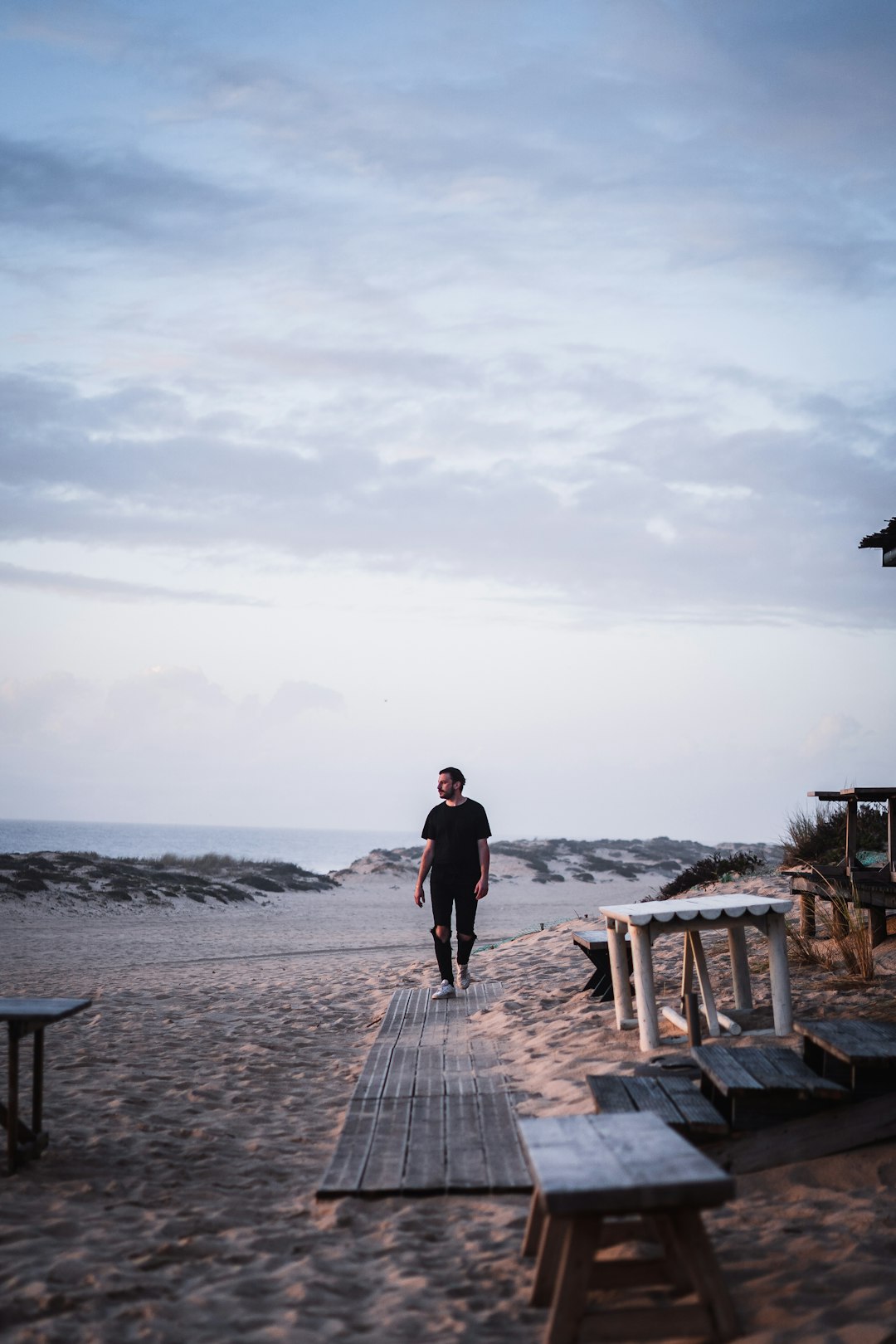 man in black t-shirt and black shorts standing on brown wooden dock during daytime