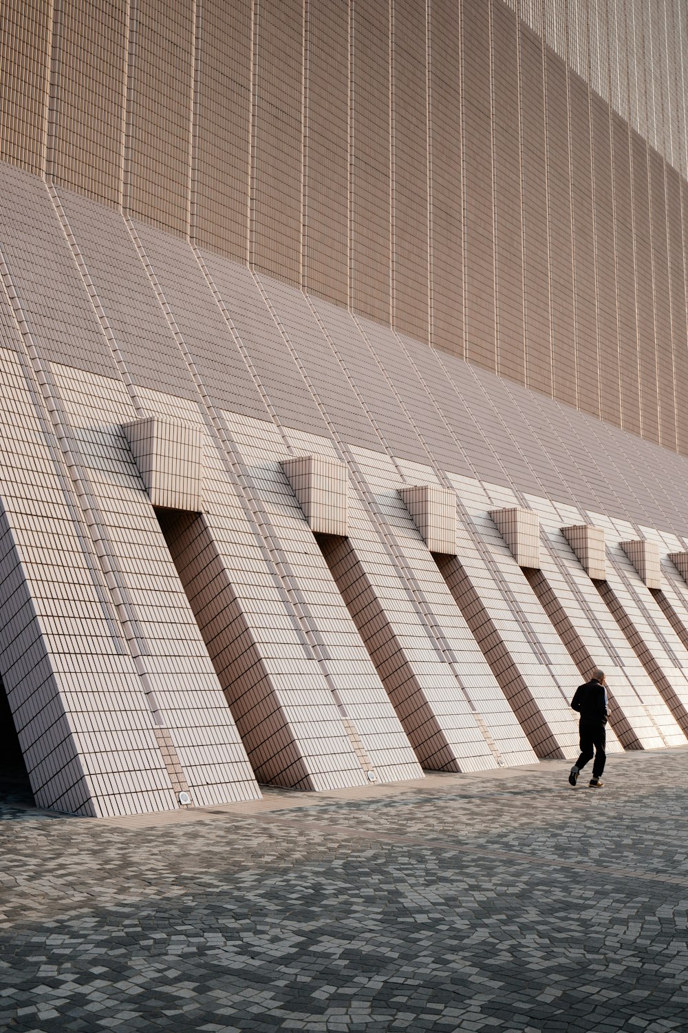 man in black jacket walking on white concrete floor