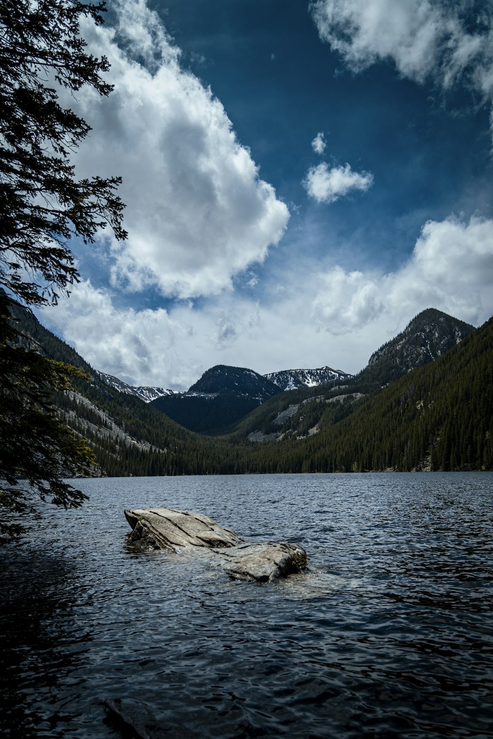 green mountains near body of water under blue and white sunny cloudy sky during daytime