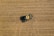 Aerial view of a green tractor harvesting a golden-brown field, with a trail indicating its movement. The field is uniformly covered with crop residue, and the tractor appears to be in operation, collecting grains.