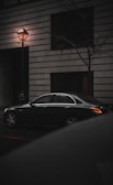 A sleek black sedan parked on a city street at dusk.
