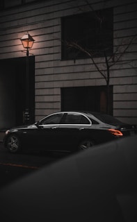 A sleek black sedan parked on a city street at dusk.