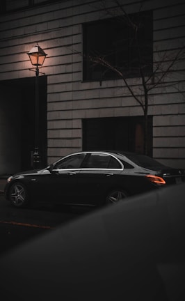 A sleek black sedan parked on a city street at dusk.