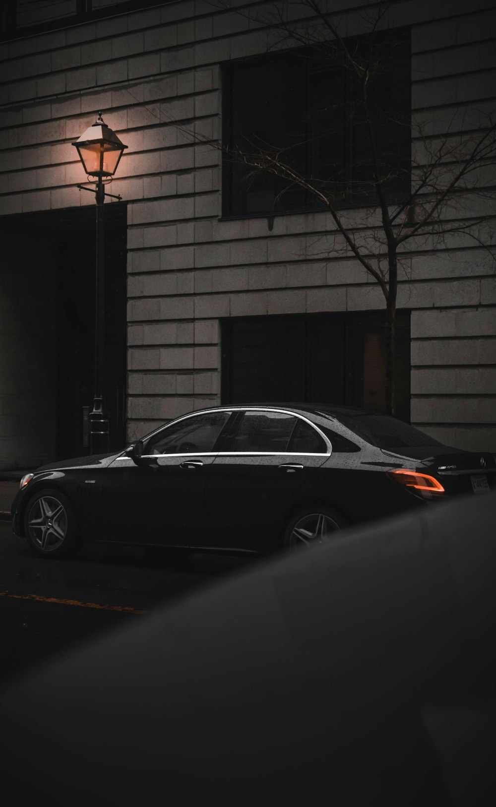 black sedan parked beside brown brick wall