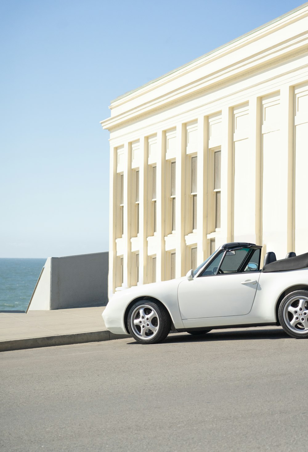 white coupe parked beside white concrete building during daytime