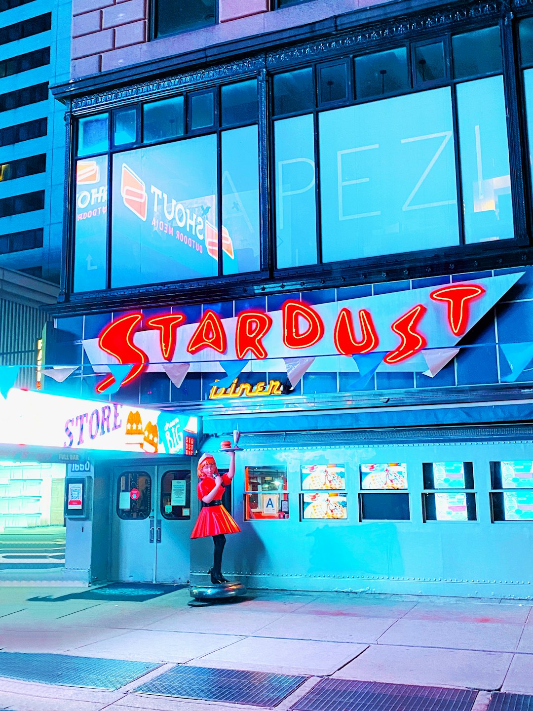 man in red shirt standing in front of store during night time