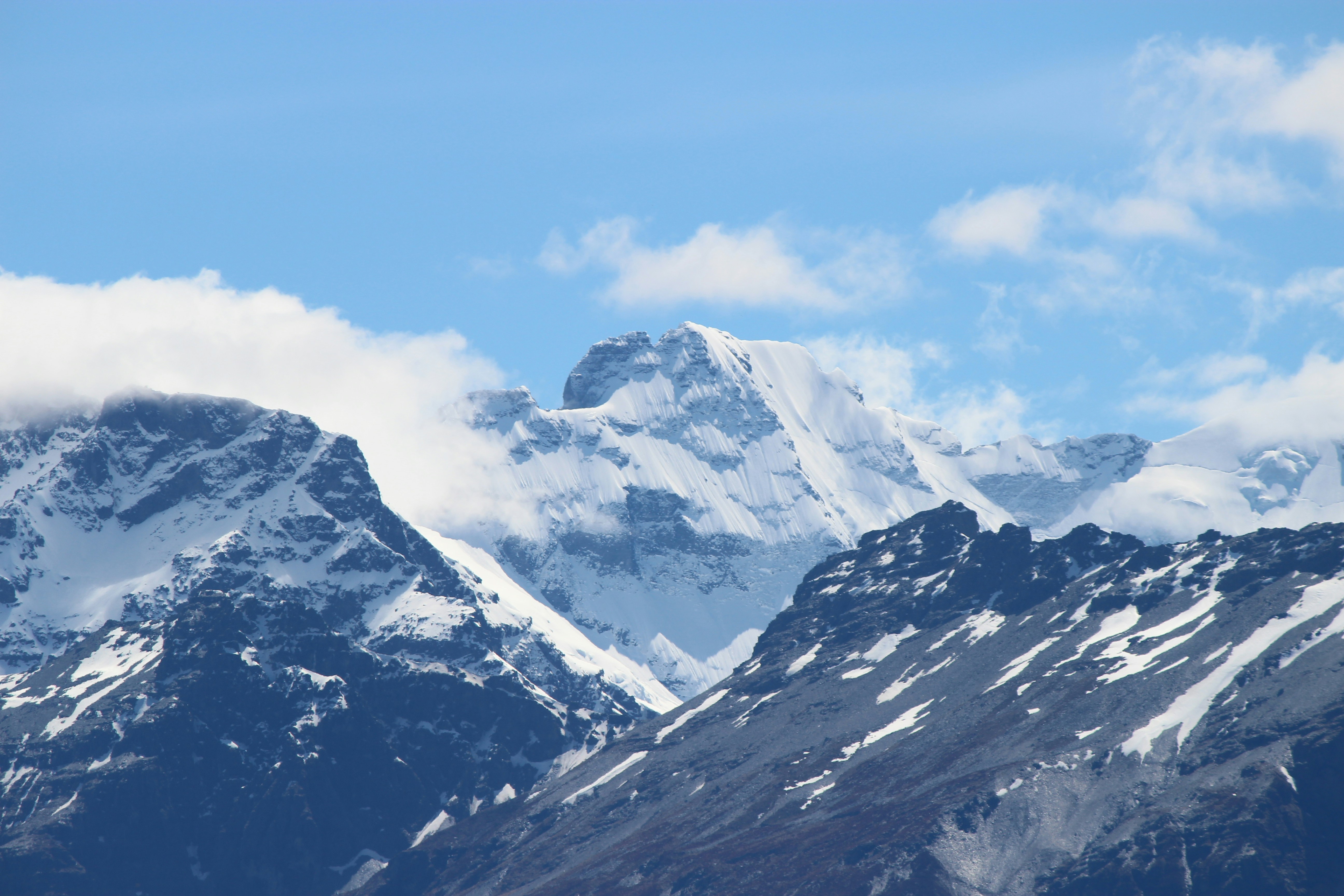 schneebedeckter Berg unter weißen Wolken und blauem Himmel tagsüber