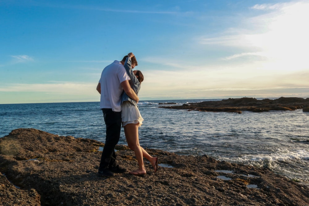 man and woman kissing on seashore during daytime