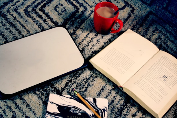 A student studying with books and a laptop, surrounded by notes and a cup of tea.