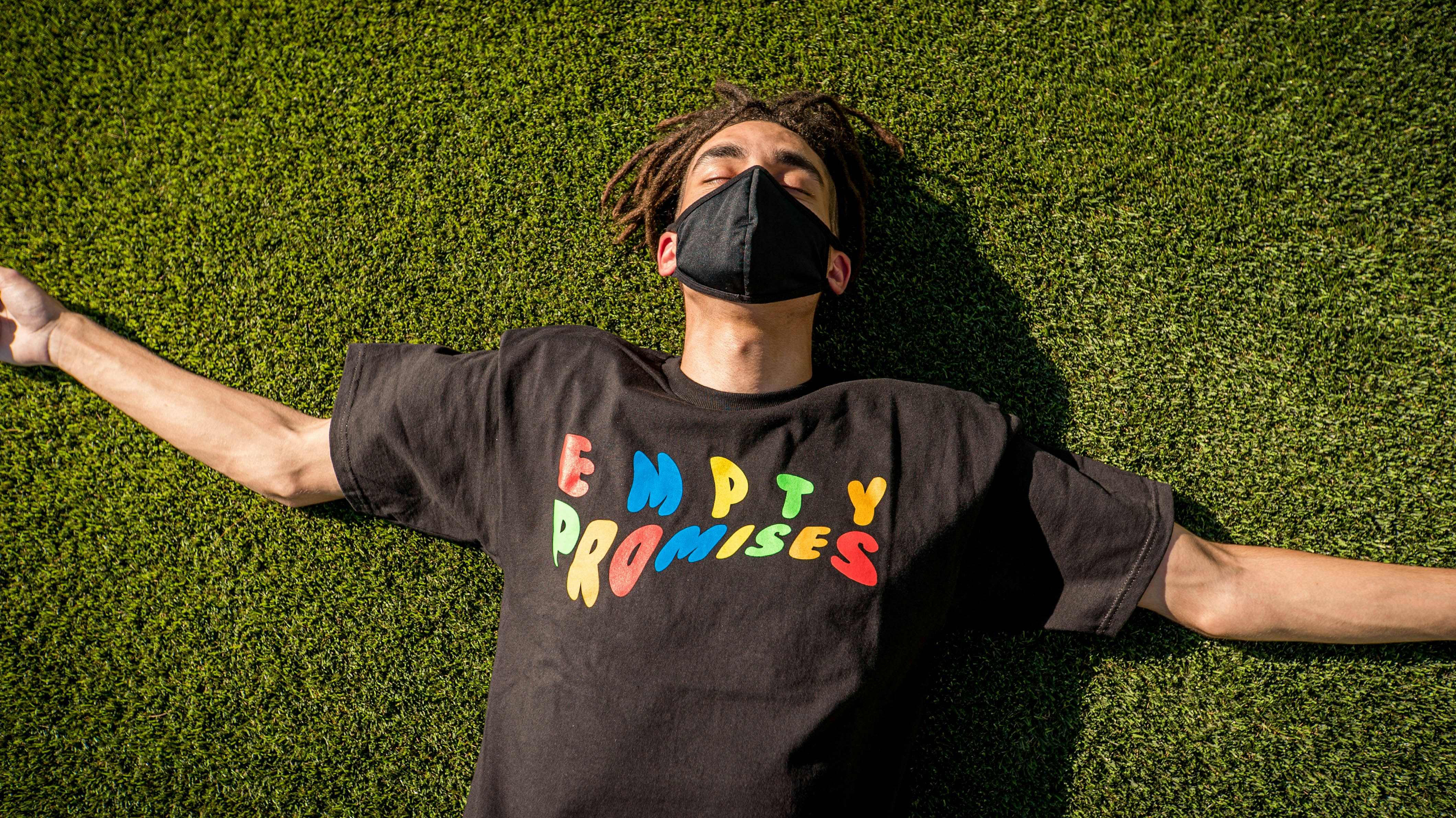 man in black and blue crew neck long sleeve shirt lying on green grass field during