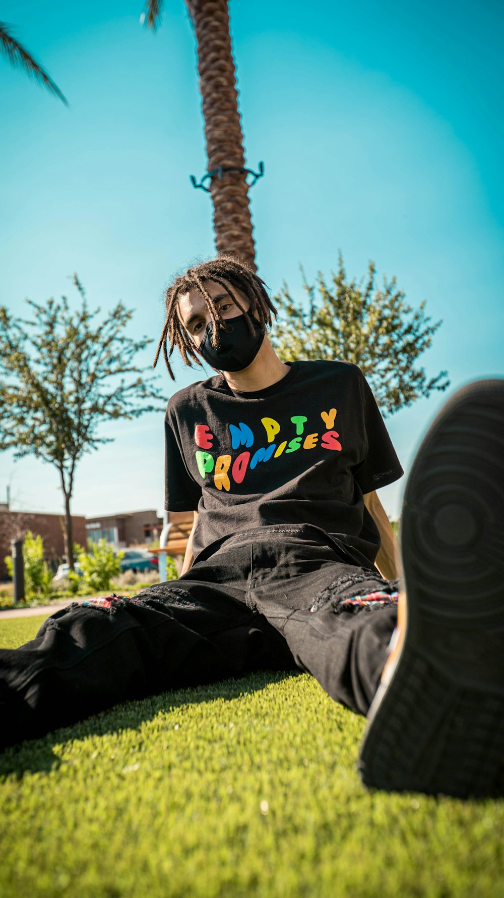 man in black crew neck t-shirt and black pants sitting on green grass field during