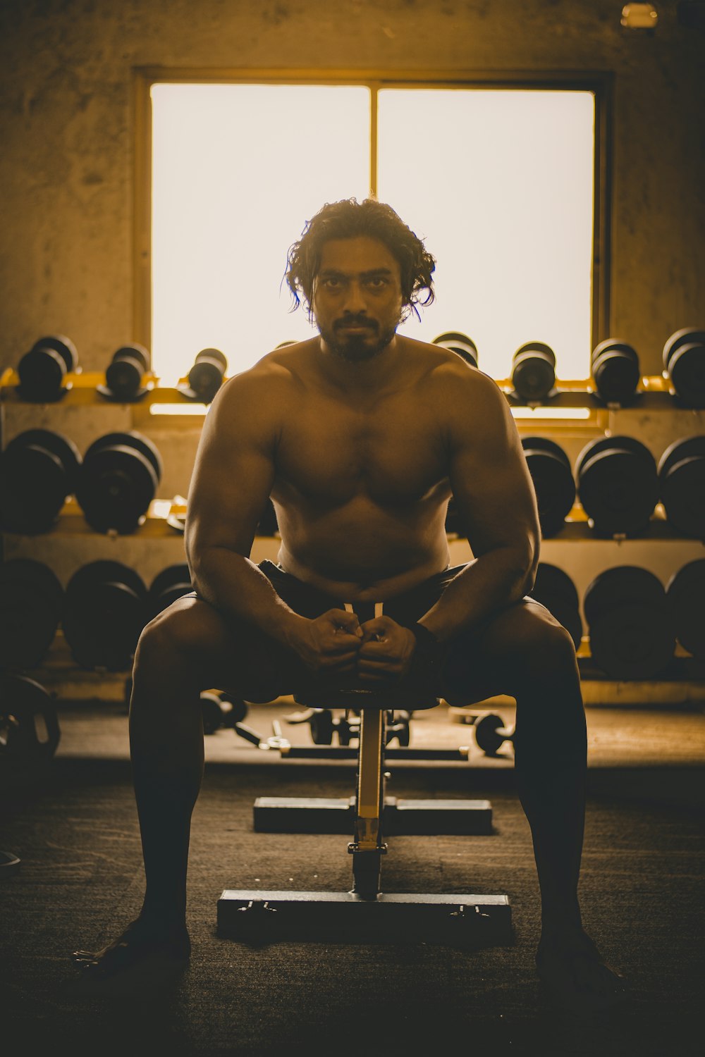 topless man sitting on exercise equipment