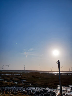 Wind turbines spinning on a sunny day in a wide open field.