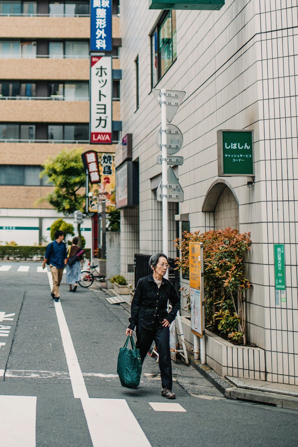 man in black jacket and green backpack walking on pedestrian lane during daytime