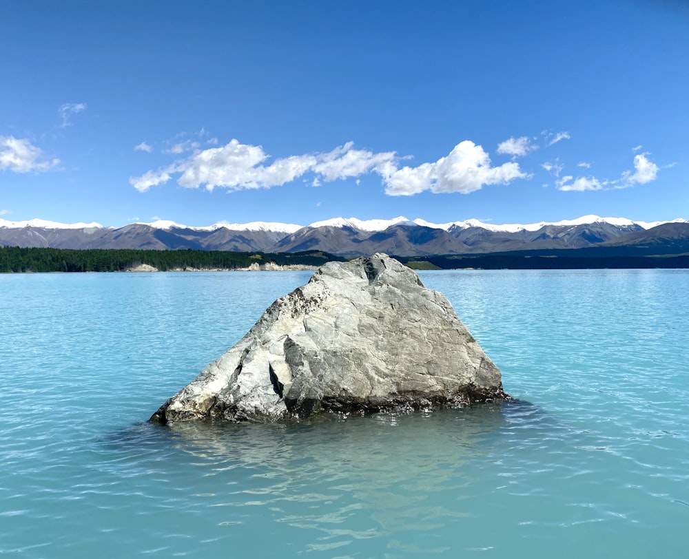 brown rock formation on body of water under blue sky during daytime