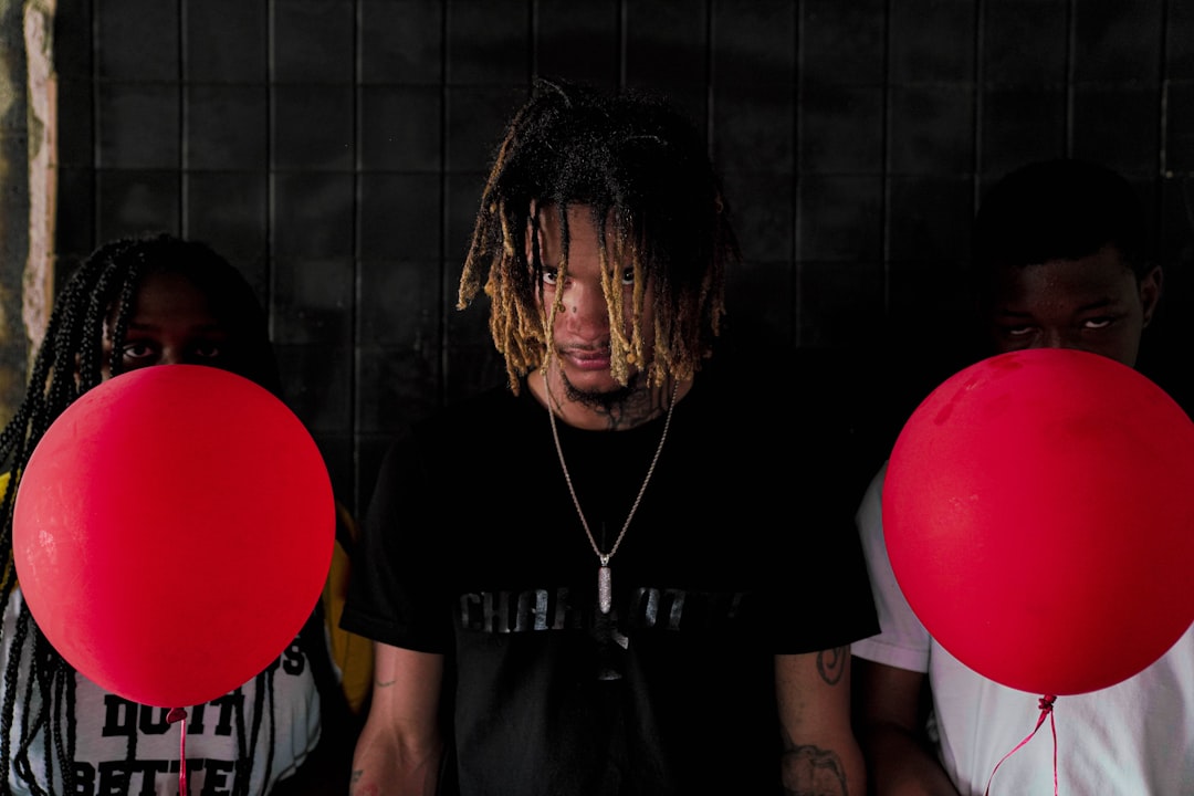 man in black crew neck t-shirt standing beside red balloon