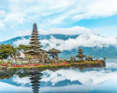 brown and green temple near body of water under blue and white cloudy sky during daytime