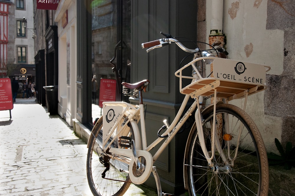 brown city bike parked beside brown concrete building during daytime