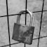 grayscale photo of padlock on metal fence