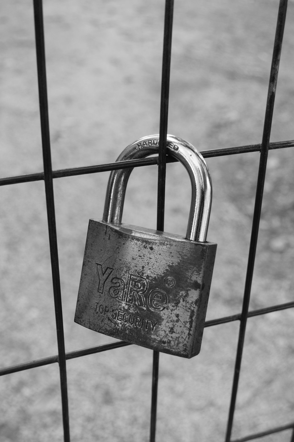 Photo en niveaux de gris d’un cadenas sur une clôture en métal