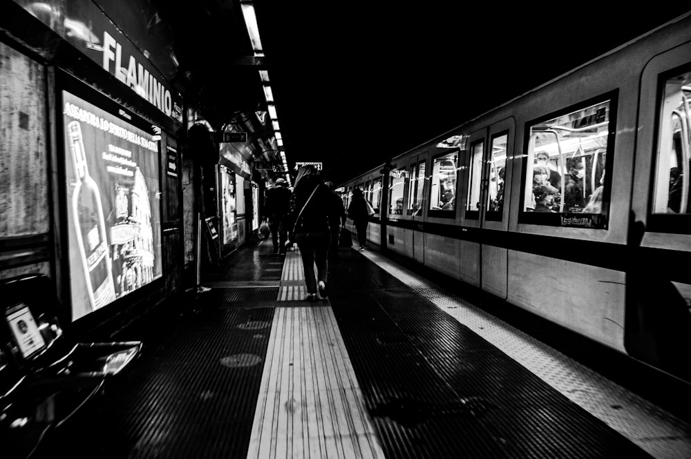 grayscale photo of people walking on train station