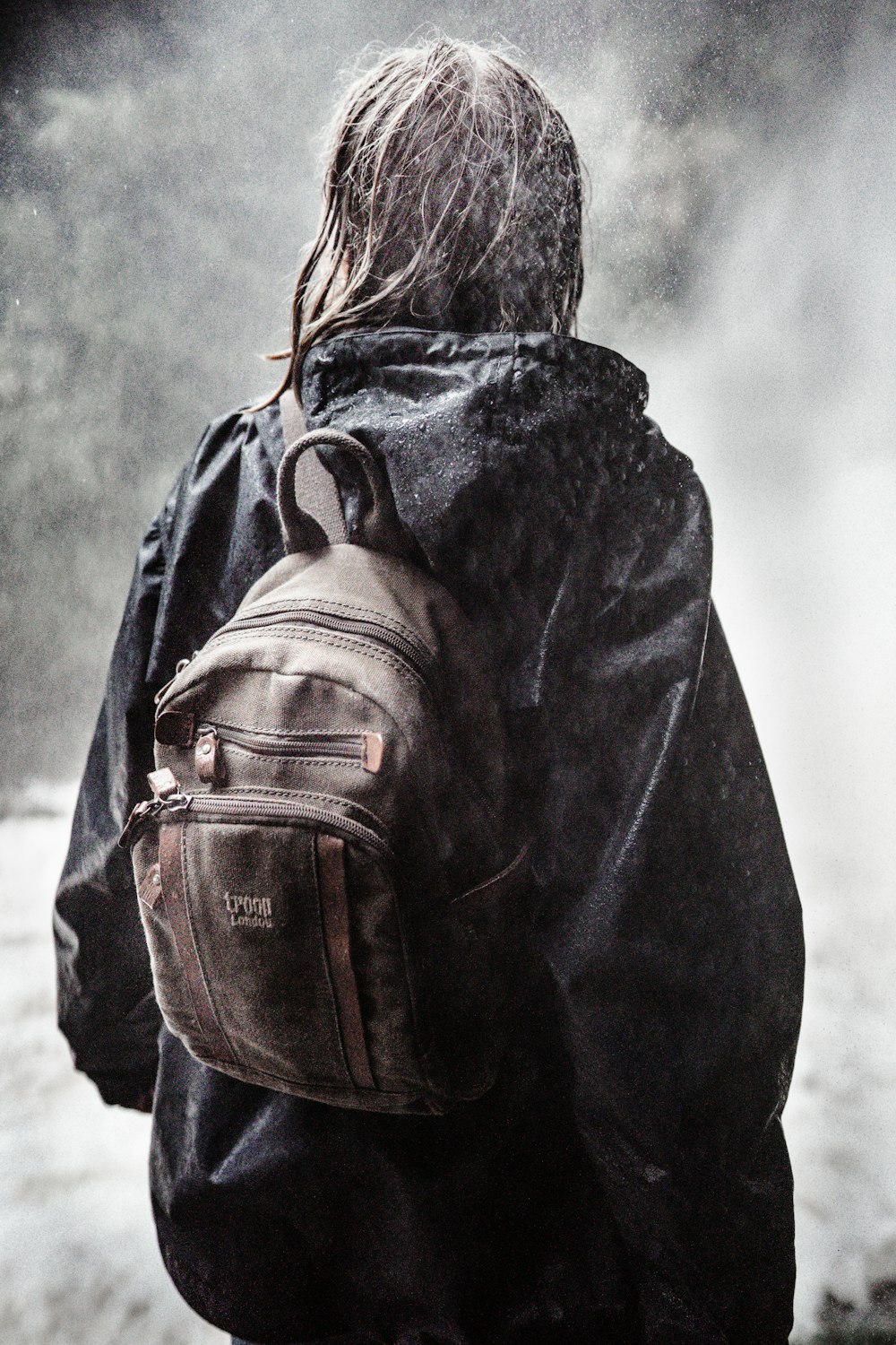 Femme en sweat à capuche noir avec sac à dos en cuir marron