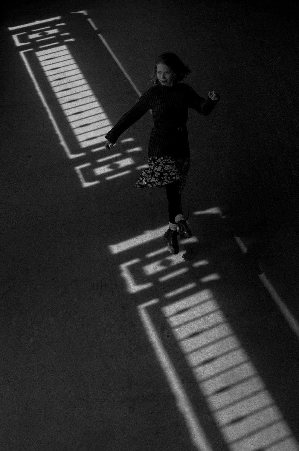 grayscale photo of woman walking on pedestrian lane