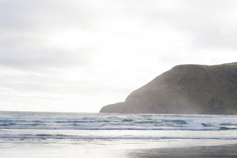 black rock formation on sea under white clouds during daytime