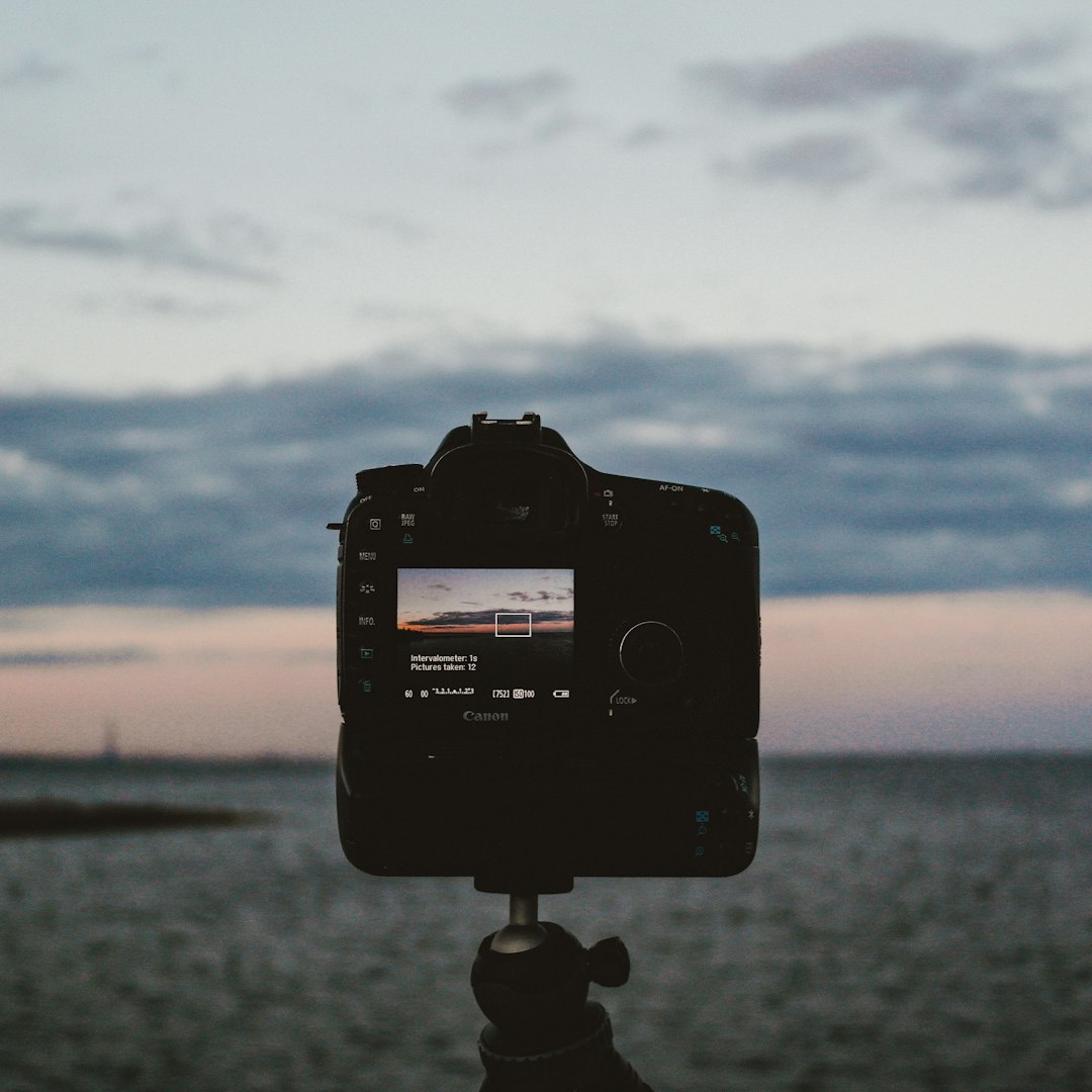 black dslr camera taking photo of body of water during daytime