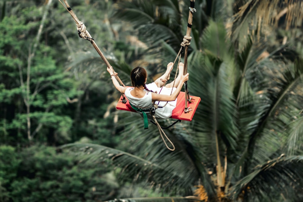 woman in white shirt sitting on swing during daytime