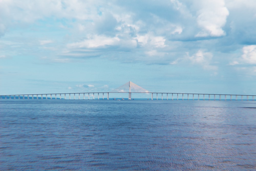 white bridge over the sea under white clouds during daytime