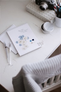 white and green floral book page beside white ceramic mug on white table
