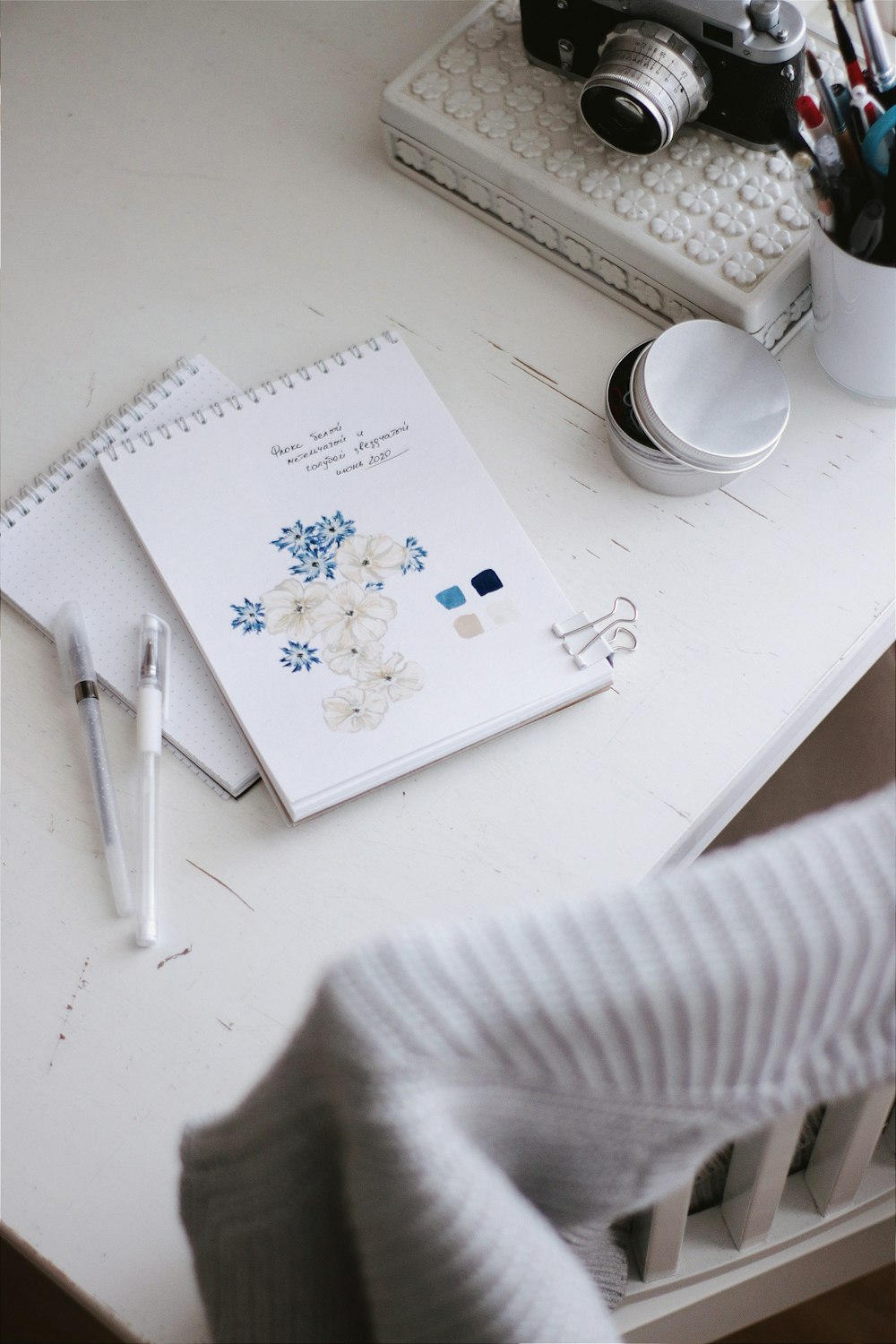 white and green floral book page beside white ceramic mug on white table