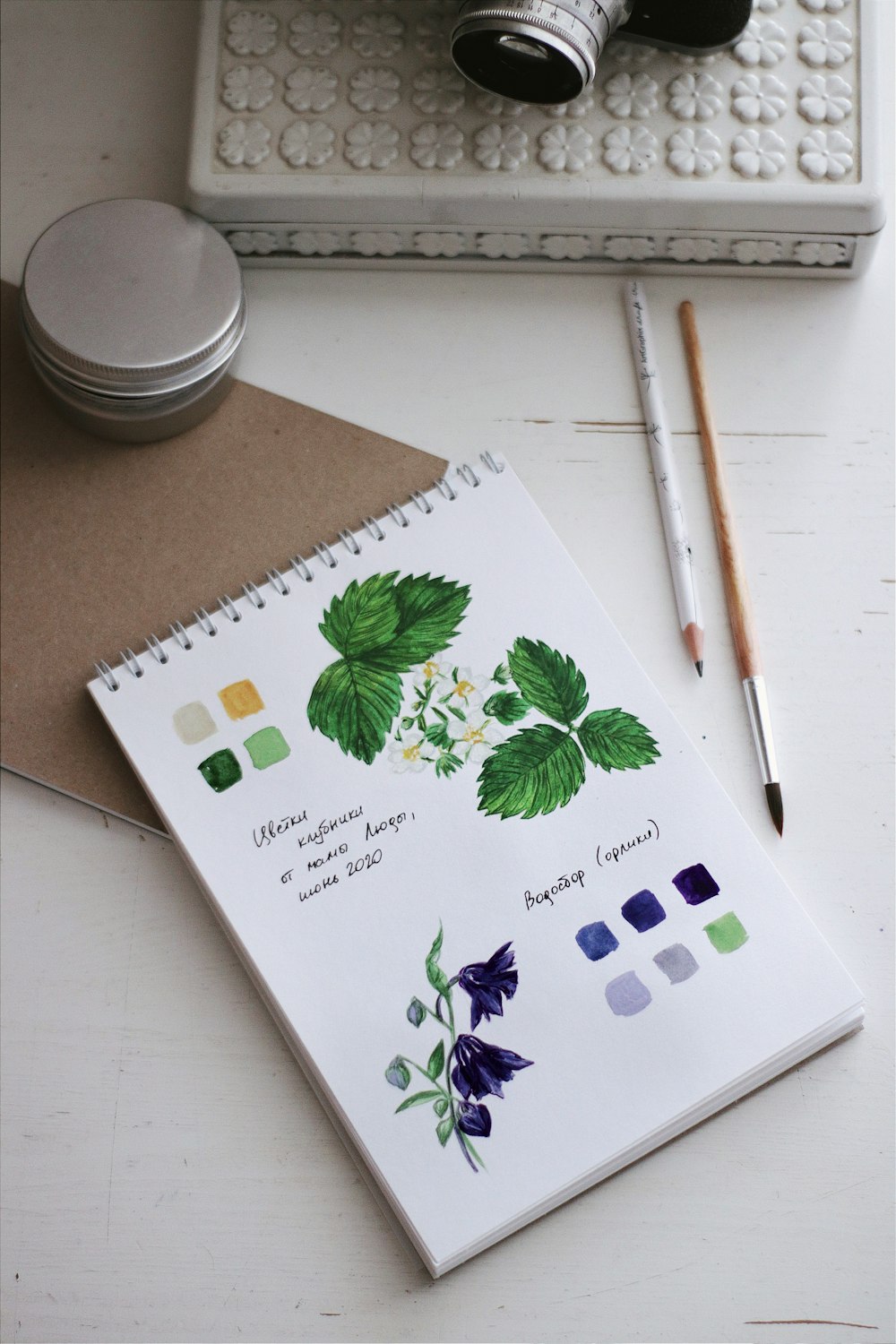 Livre floral blanc et vert à côté du crayon brun