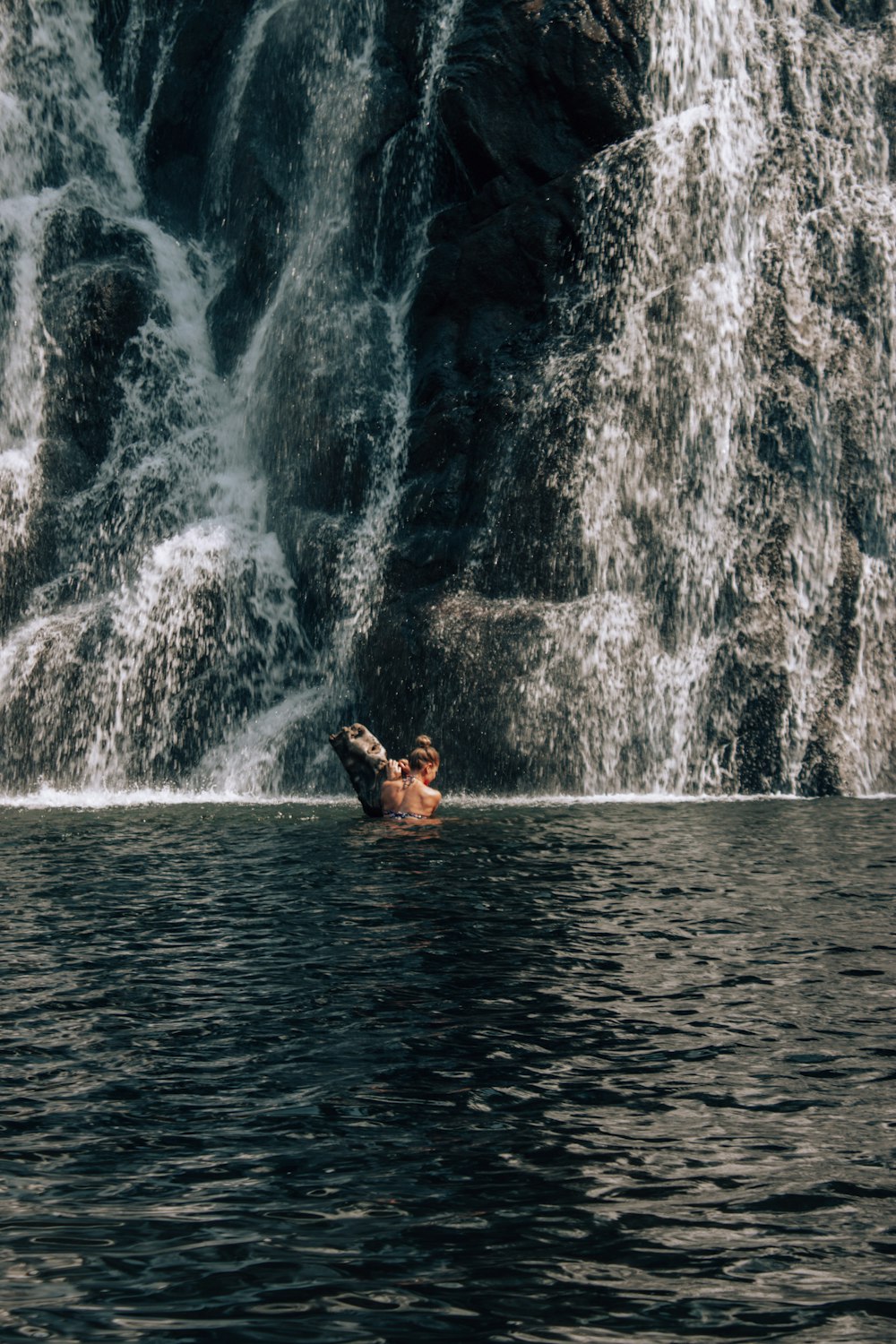 woman in black bikini lying on water falls during daytime