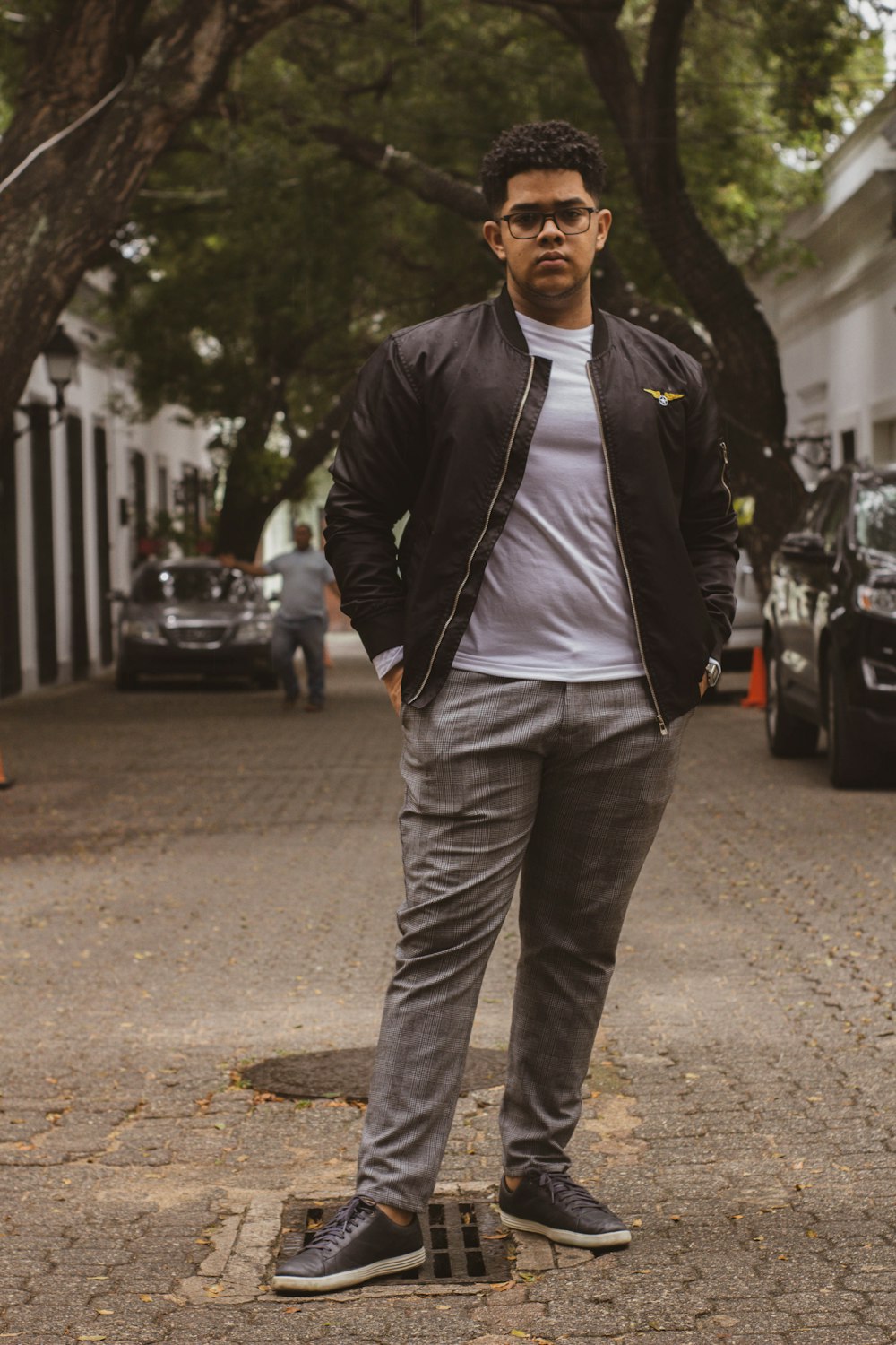 man in black leather jacket and gray pants standing on road during daytime