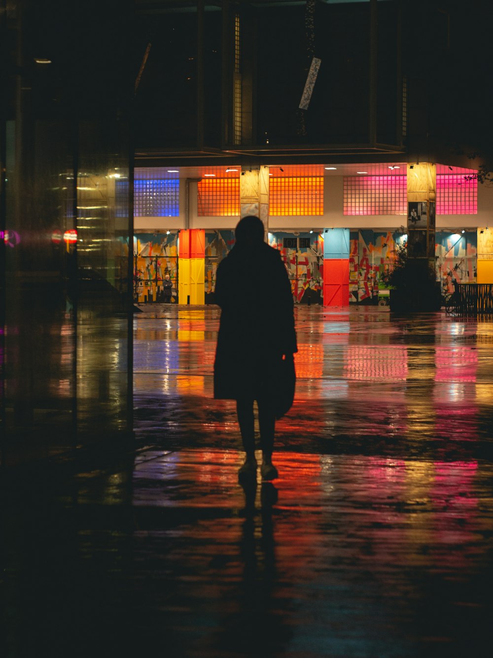 silhouette of person walking on sidewalk during night time