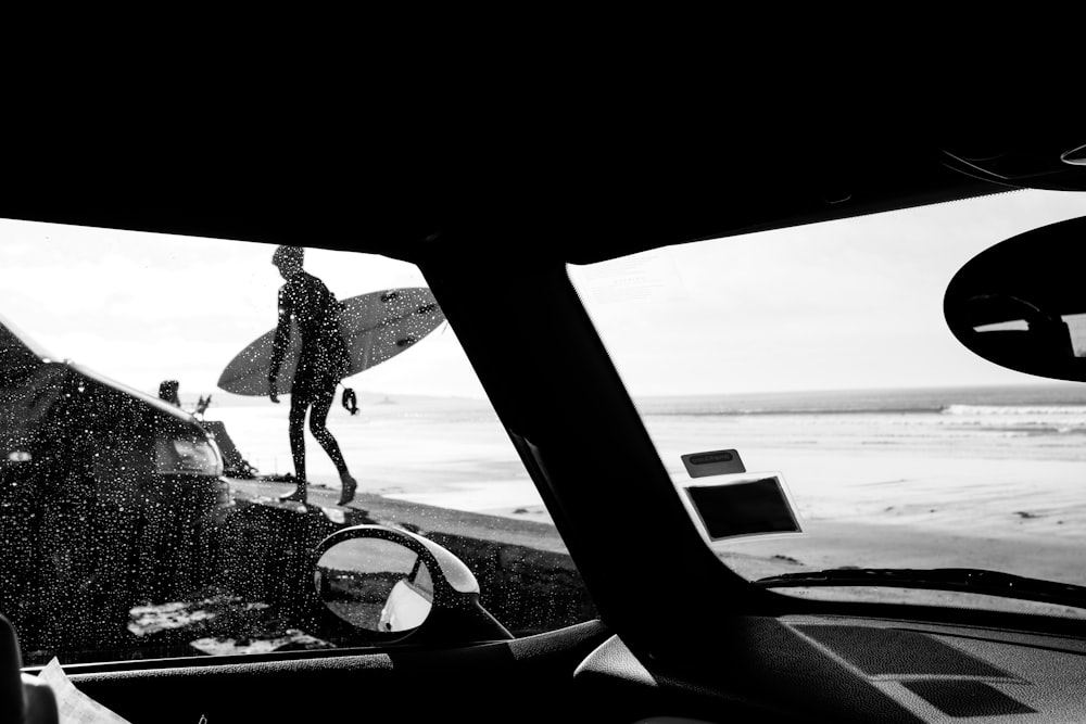 grayscale photo of woman in long sleeve shirt and pants standing on beach